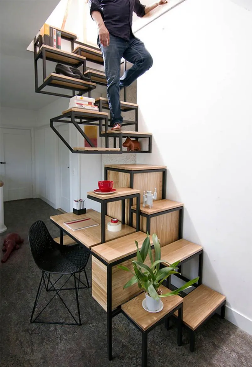 Man climbing wood stairs with black metal frames that serve as a desk and shelves