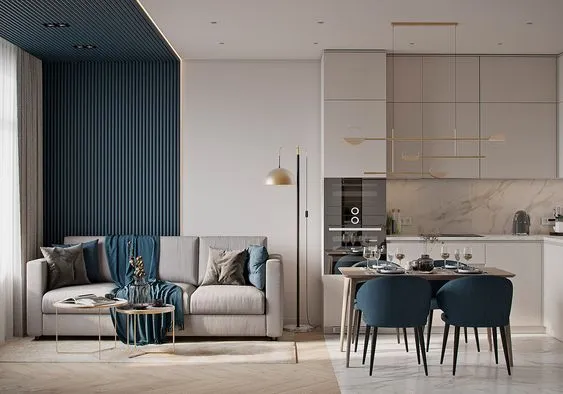 Modern living space with grey sofa blue wall panel dining area and white kitchen cabinets