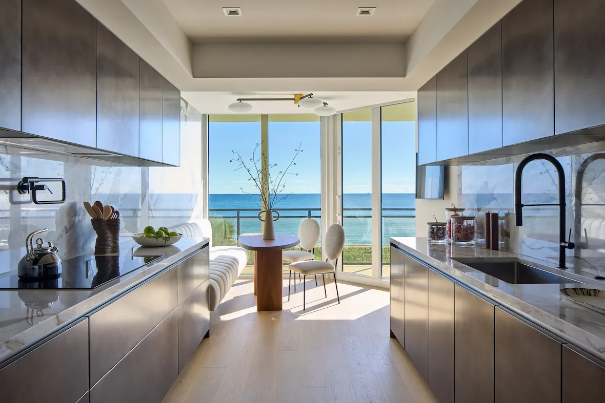 Modern kitchen with metal cabinets and dining table overlooking a beautiful blue ocean water view