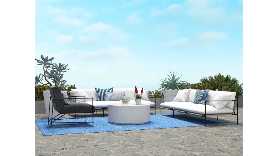 Modern outdoor terrace with white sofas blue rug round coffee table and plants under sky