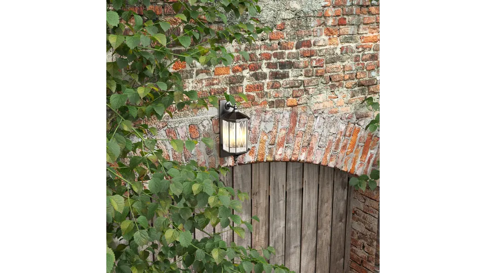 Outdoor wall light on aged brick wall with green climbing plants above an arched gate