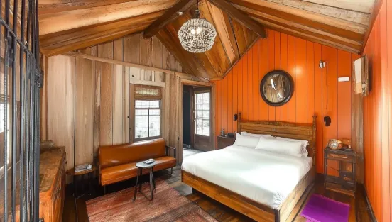 Rustic bedroom with orange wall wood wall panel white bed leather sofa and ceiling light